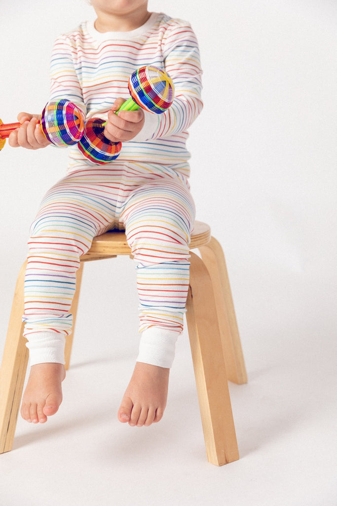 a little kid wearing dodo banana rainbow striped pima cotton pajamas